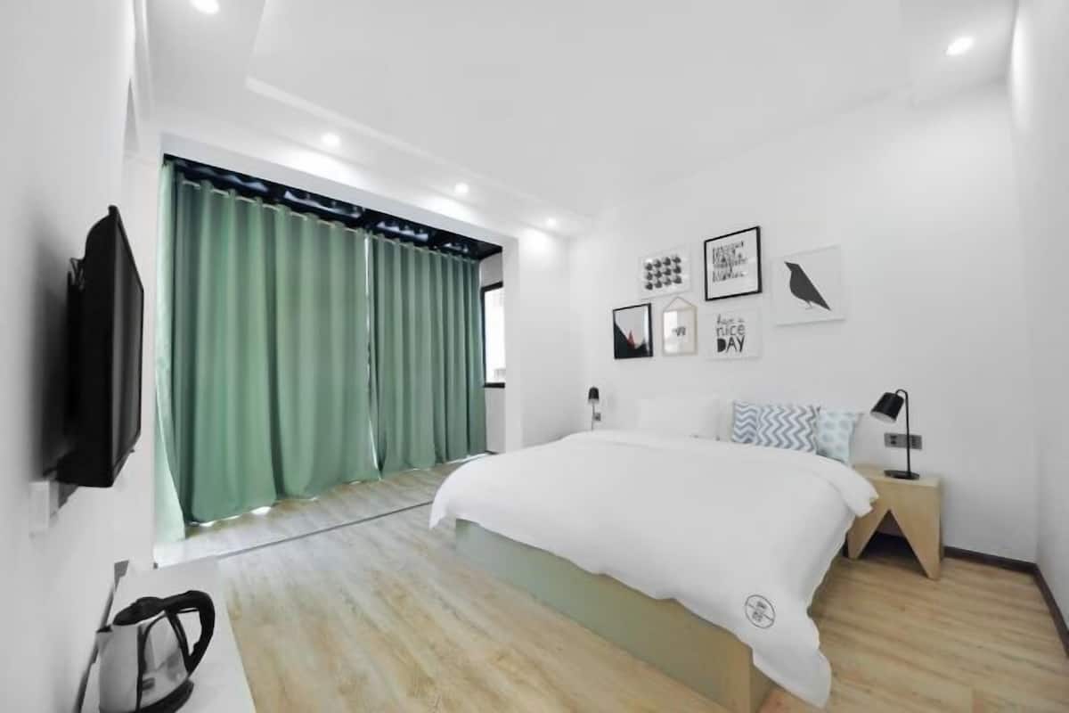 A modern bedroom with a bed, a nightstand, a lamp, and a wall-mounted TV.