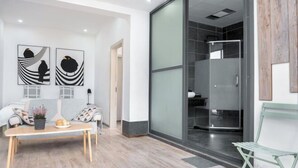 A modern interior with a sofa, a table with decorative items, and a glass shower area. - Xiaochengshanyue Inn ((Dali Ancient City South Gate) (Dali City)