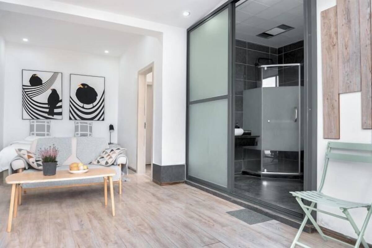 A modern interior with a sofa, a table with decorative items, and a glass shower area.