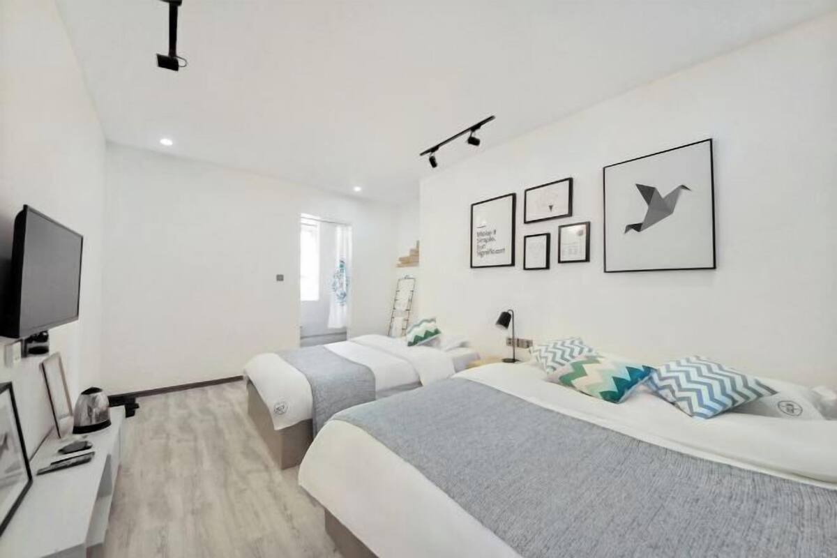 A modern hotel room with two beds, a flat-screen TV, and wall-mounted artwork.