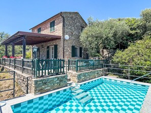 Un bâtiment en pierre doté d’une piscine, d’un patio couvert et d’un mur en pierre.