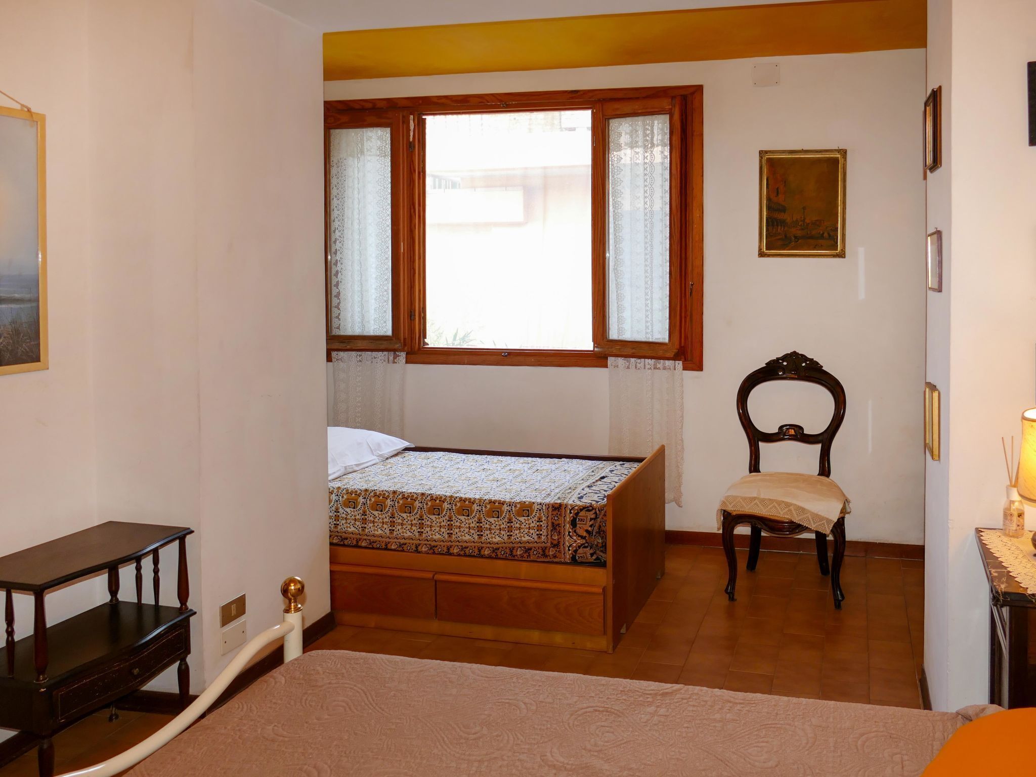 A bedroom with a bed, a chair, a desk, and a window with curtains.
