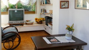 A cozy living room with a television, bookshelves, and a coffee table. - Francesca by Interhome (Sanremo)