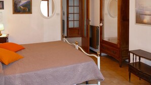 A bedroom with a bed, a wooden wardrobe, a mirror, and a framed picture on the wall. - Francesca by Interhome (Sanremo)