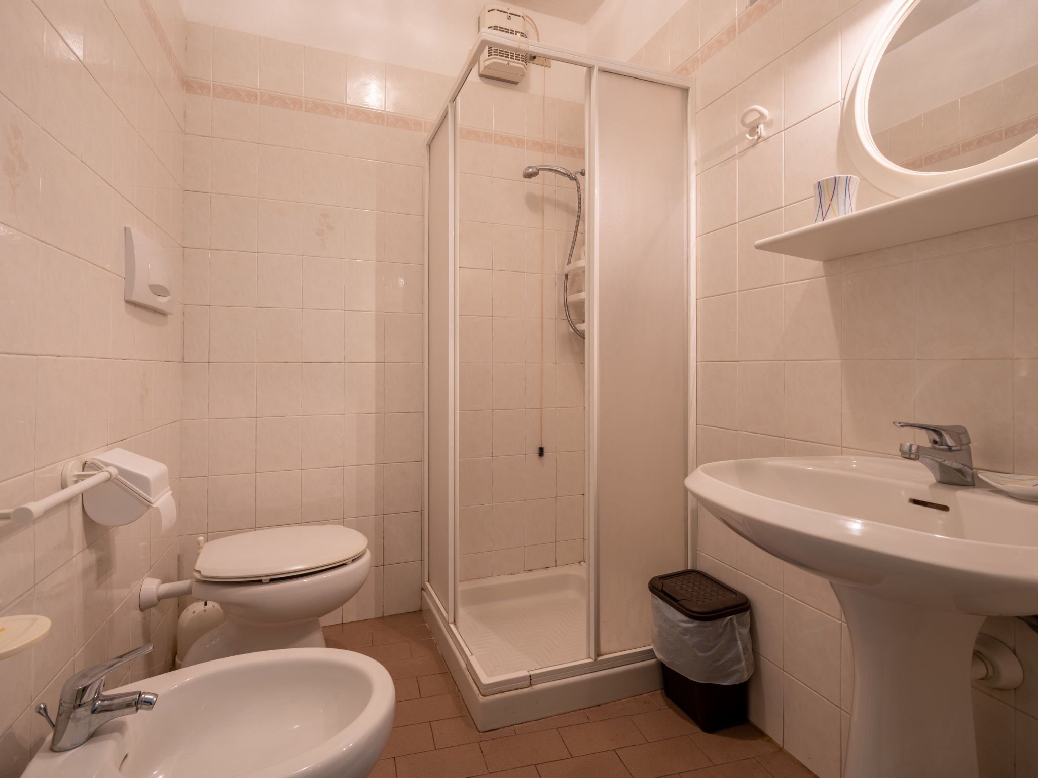 A bathroom with a toilet, bidet, sink, and shower.