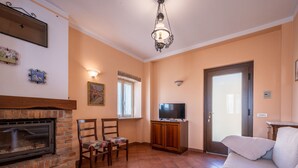 A living room with a fireplace, two chairs, a sofa, a television, and a door. - Bricco dei Ciliegi by Interhome (Cortazzone)