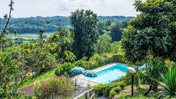 A pool surrounded by lush greenery and a view of distant hills. - Bricco dei Ciliegi by Interhome (Cortazzone)