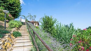 A stone staircase leading up a hill, surrounded by lush greenery and flowers. - Bricco dei Ciliegi by Interhome (Cortazzone)
