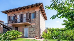A two-story building with a balcony, stone facade, and a well-maintained garden. - Bricco dei Ciliegi by Interhome (Cortazzone)