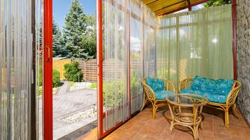 Une terrasse couverte, aménagée avec des meubles en osier, donnant sur le jardin arrière.