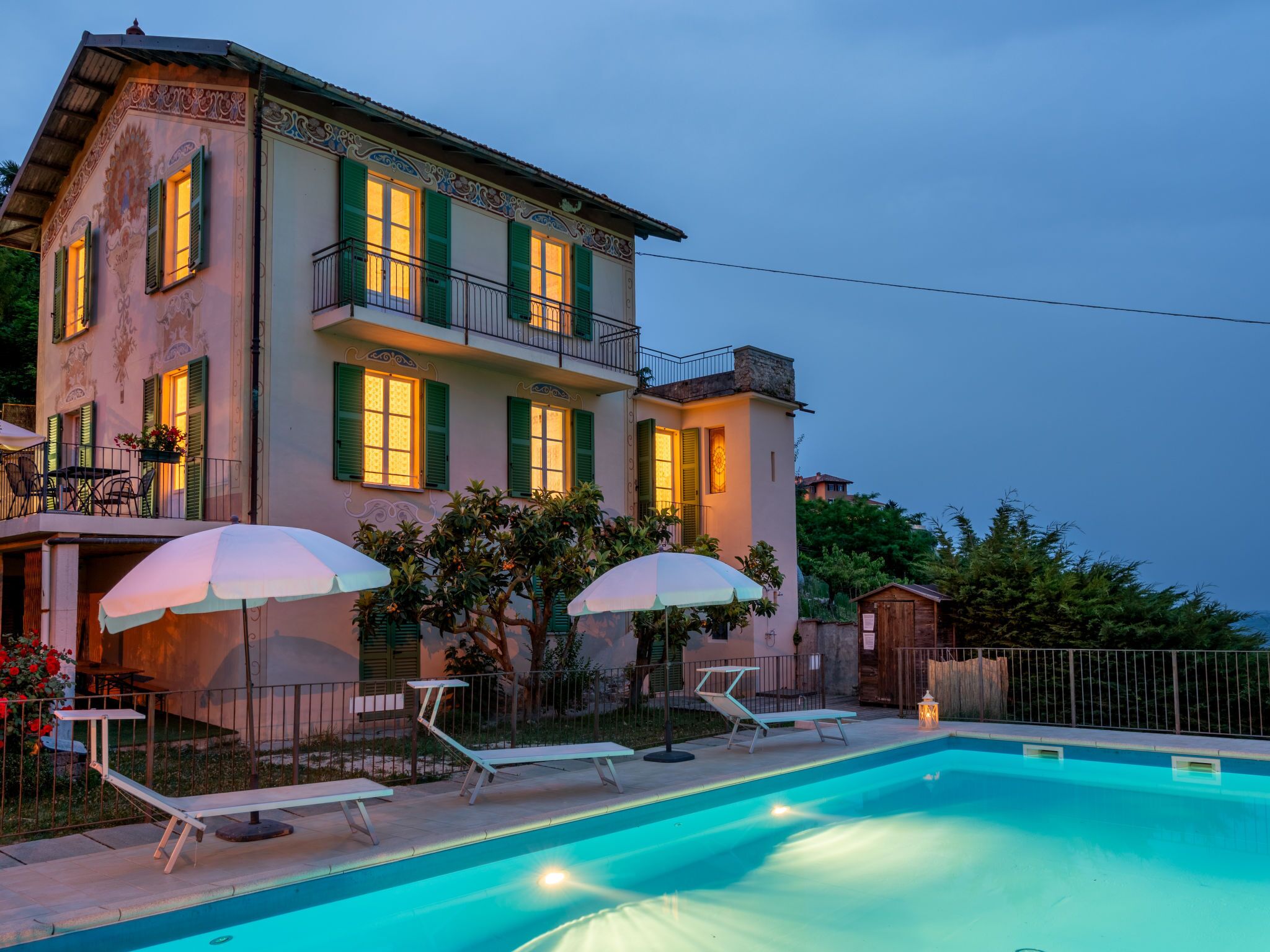 A two-story building with a swimming pool, outdoor seating, and a balcony.