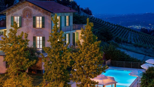 Una villa con piscina, rodeada de árboles y con vistas a un viñedo.