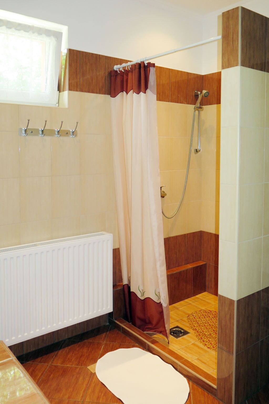 A bathroom with a shower, a radiator, and a wooden floor.