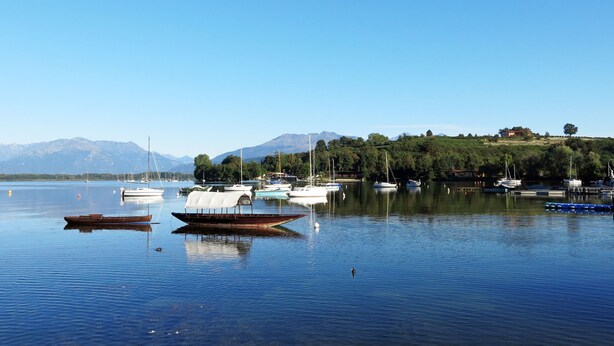 A calm lake with boats and a mountain in the background.