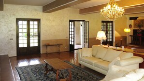 A spacious living room with a white sofa, a wooden coffee table, and a chandelier.
