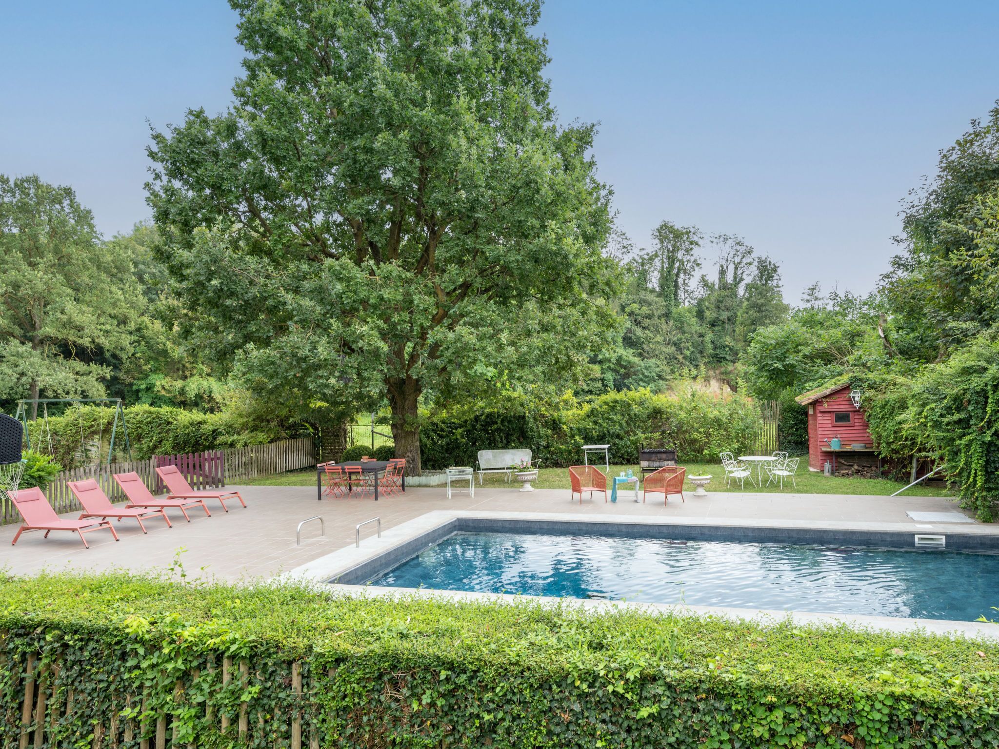 Une piscine entourée de chaises longues et d’un bâtiment rouge.
