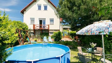 Et hus med swimmingpool, træterrasse og terrasse med udendørs møbler.
