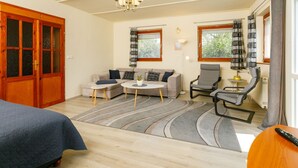 Una sala de estar acogedora con sofá, dos sillones, una mesita de centro y una araña.