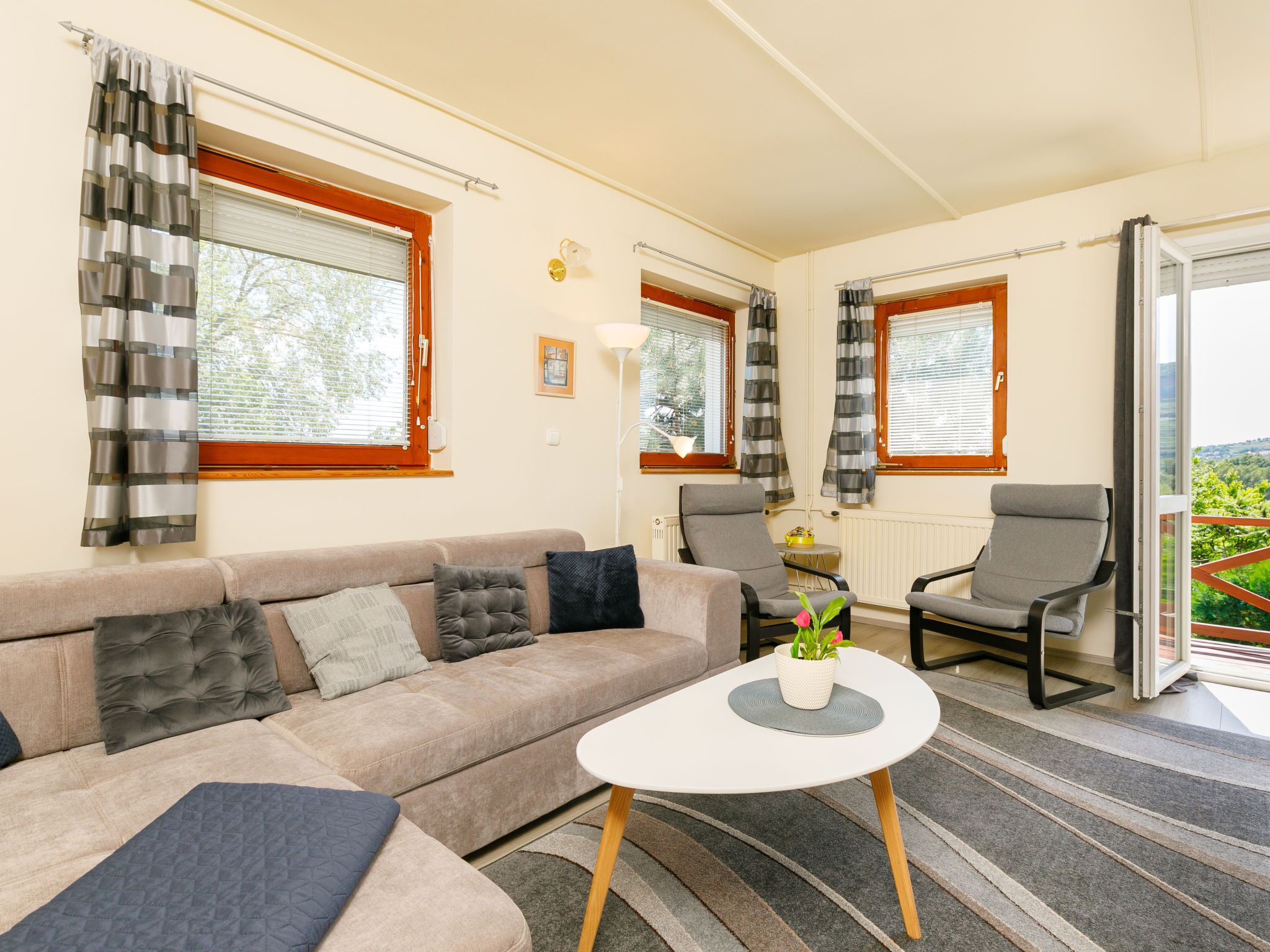 En stue med sofa, to lænestole, sofabord og udsigt til det fri via en skydedør.