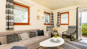 Una sala de estar con un sofá, dos sillones, una mesa de centro y vistas al exterior a través de un ventanal corredero.