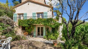 A two-story house with a stone facade, green shutters, and a covered patio area with outdoor furniture. - La Garance by Interhome (Grasse)