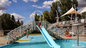 Un parc aquatique avec un toboggan bleu, une piscine et une tour de surveillance pour les sauveteurs.