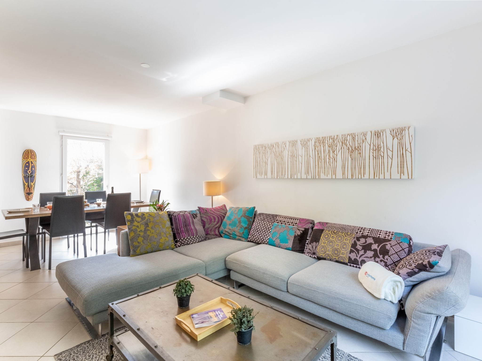 Uma sala de estar moderna com sofá seccional, mesa de jantar e mesa de centro.