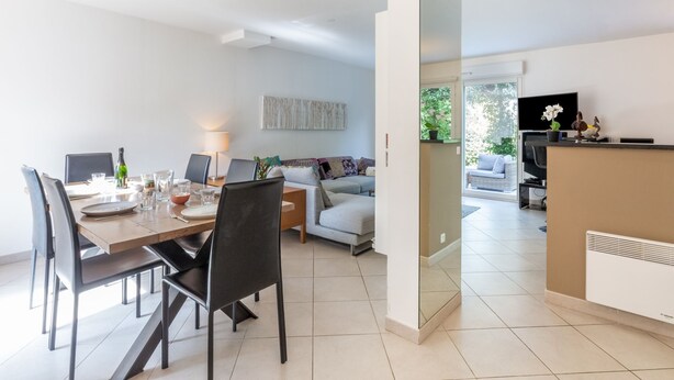 A modern living room with a dining area, a sofa, a TV, and a kitchen area. - Les Rives du Golf 3 by Interhome (Roquebrune sur Argens)