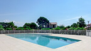 A rectangular swimming pool with a tiled deck, surrounded by a metal fence and lush greenery. - Les Rives du Golf 3 by Interhome (Roquebrune sur Argens)