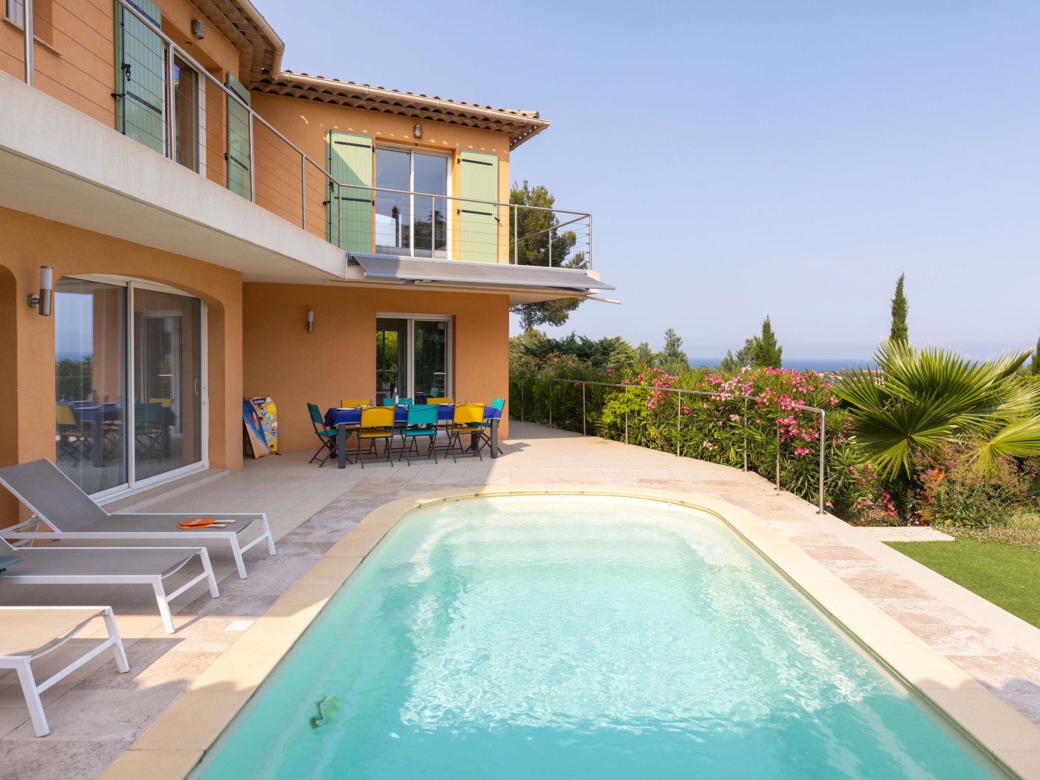 A two-story building with a swimming pool, outdoor seating, and a view of the sea.