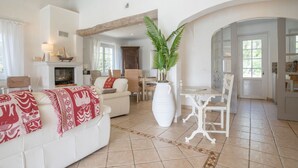 A spacious living area with a fireplace, a dining table, and a large potted plant. - La Crischona by Interhome (Les Issambres)