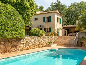 A poolside view of a building with a stone wall, a pool, and a staircase leading to a covered area. - L'Oliverede by Interhome (La Garde Freinet)