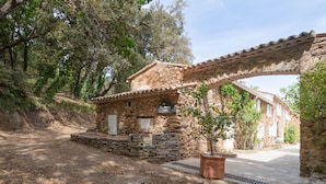A rustic stone house with a tiled roof, a small garden, and a paved entrance. - La Bastide Haute by Interhome (La Garde Freinet)