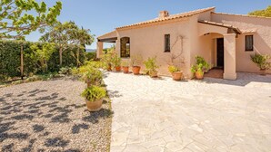 A Mediterranean-style house with a tiled roof, stone pathway, and potted plants. - Le Mas d'Olive by Interhome (Grimaud)