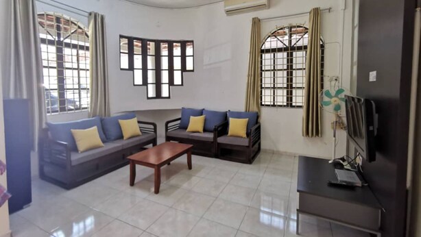 A living room with a sofa set, a coffee table, and a TV stand. - OYO 91031 House No 8 (Muar)