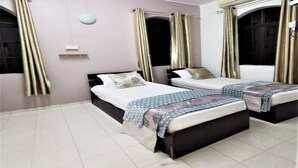 A room with two beds, a small window, and a ceiling light. - OYO 91031 House No 8 (Muar)