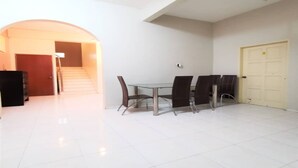 A spacious room with a large dining table, four chairs, and a door. - OYO 91031 House No 8 (Muar)