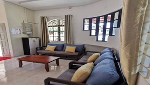 A living room with a sofa set, a coffee table, and a window with curtains. - OYO 91031 House No 8 (Muar)