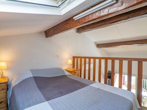 Cozy retreat with a sloped ceiling, exposed beams, and a skylight above the bed.