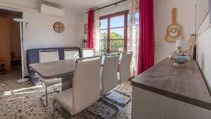 A dining area with a table and chairs, a clock, a window with curtains, and a guitar on the wall. - Villa Marenco by Interhome (La Croix-Valmer)
