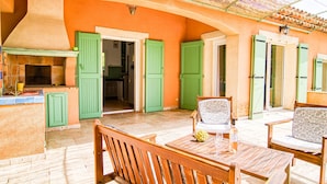 A covered patio with wooden furniture and a table set for dining.