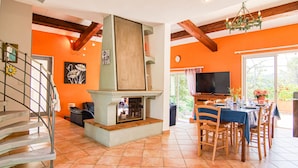 A spacious living area with a fireplace, dining table, and a staircase.