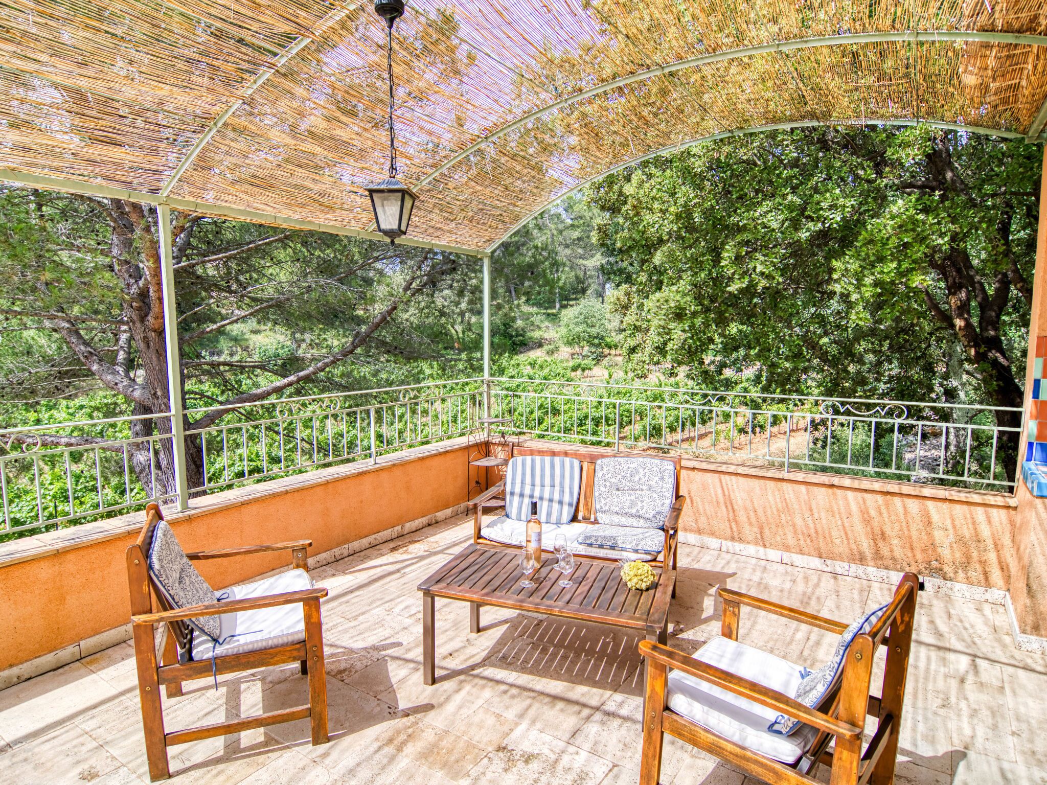 Un patio exterior con mobiliario de madera y techo de paja.