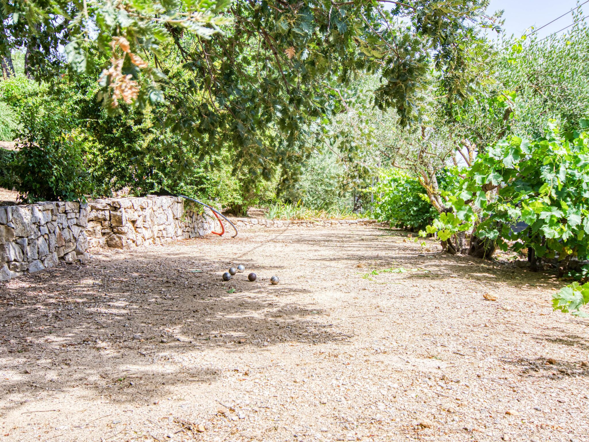 Ein Kiesweg schlängelt sich durch einen Garten mit Steinmauern und dichtem Grün.