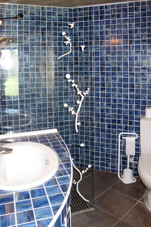 Ein Badezimmer mit blauen Mosaikfliesen, einem weißen Waschbecken und einer Toilette.