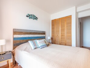 A bedroom with a bed, a nightstand, a lamp, a wooden headboard, a wardrobe, and a wall decoration. - Baie des Lecques by Interhome (Saint Cyr sur mer Les Lecques)