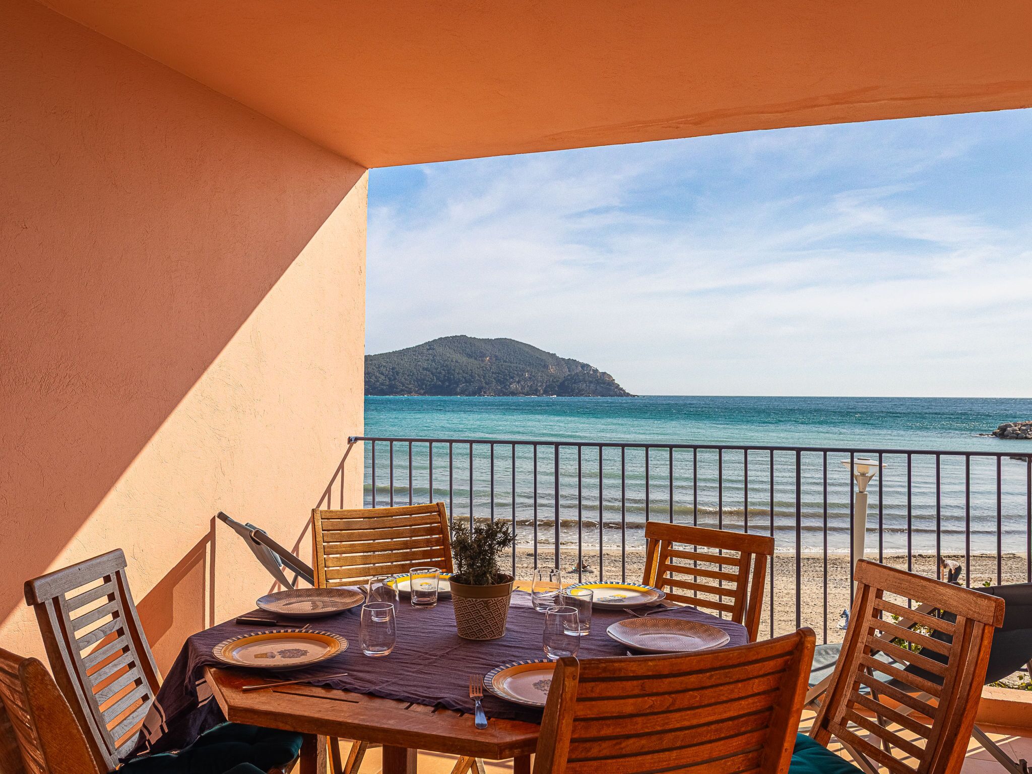 Une table dressée pour le dîner, avec vue sur la mer et une montagne en arrière-plan.