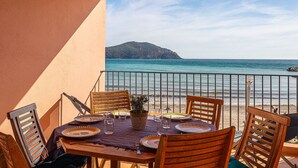 Une table dressée pour le dîner, avec vue sur la mer et une montagne en arrière-plan.