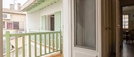 A balcony with a green railing, a sliding glass door, and a tiled floor.