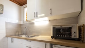 Eine moderne Küche mit weißen Schränken, einer Edelstahlspüle, einem eingebauten Toaster und einer Holzarbeitsplatte.